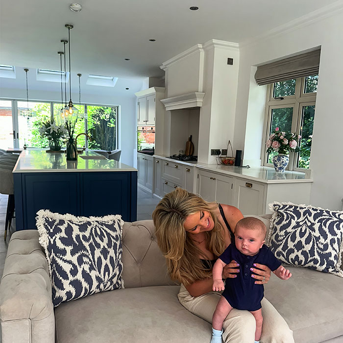 Corrie from The Spence Home and her child seated on their kitchen sofa